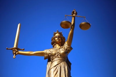 Statue of Lady Justice holding scales and sword with blue sky background